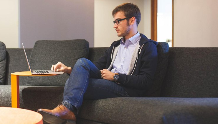 Persona al lavoro seduta su un divano