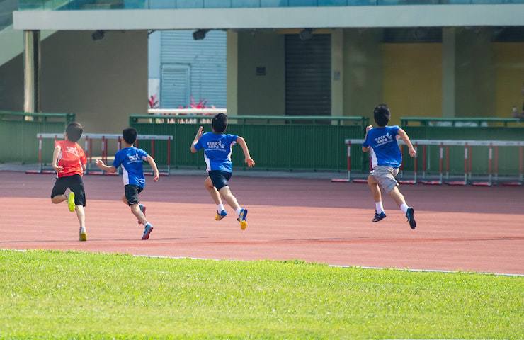 Bambini di spalle che corrono su una pista di atletica