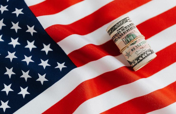 Mazzetta di dollari americani appoggiati sulla bandiera degli Stati Uniti