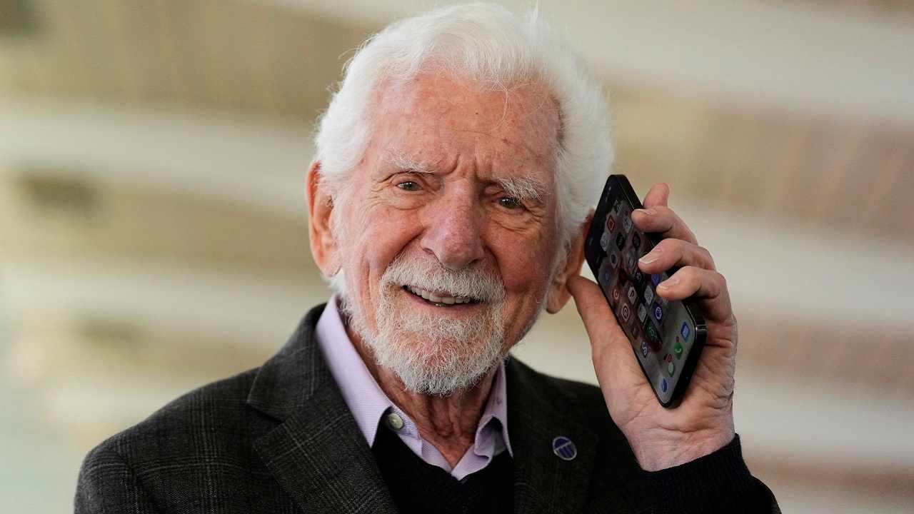 Martin Cooper mentre tiene in mano un moderno smartphone