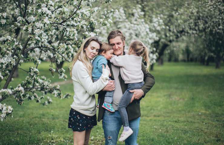 Famiglia composta da due genitori e due bambini stretta in un abbraccio in giardino