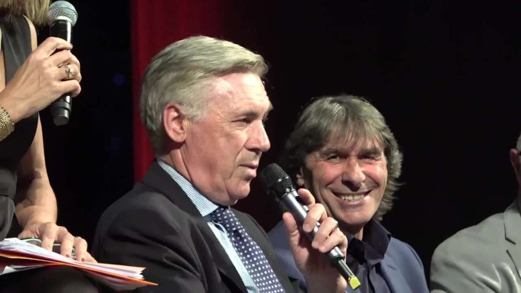 Carlo Ancelotti parla al microfono al fianco di Bruno Conti a un evento organizzato dalla Roma