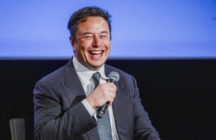 Elon Musk ride mentre parla al microfono a una conferenza