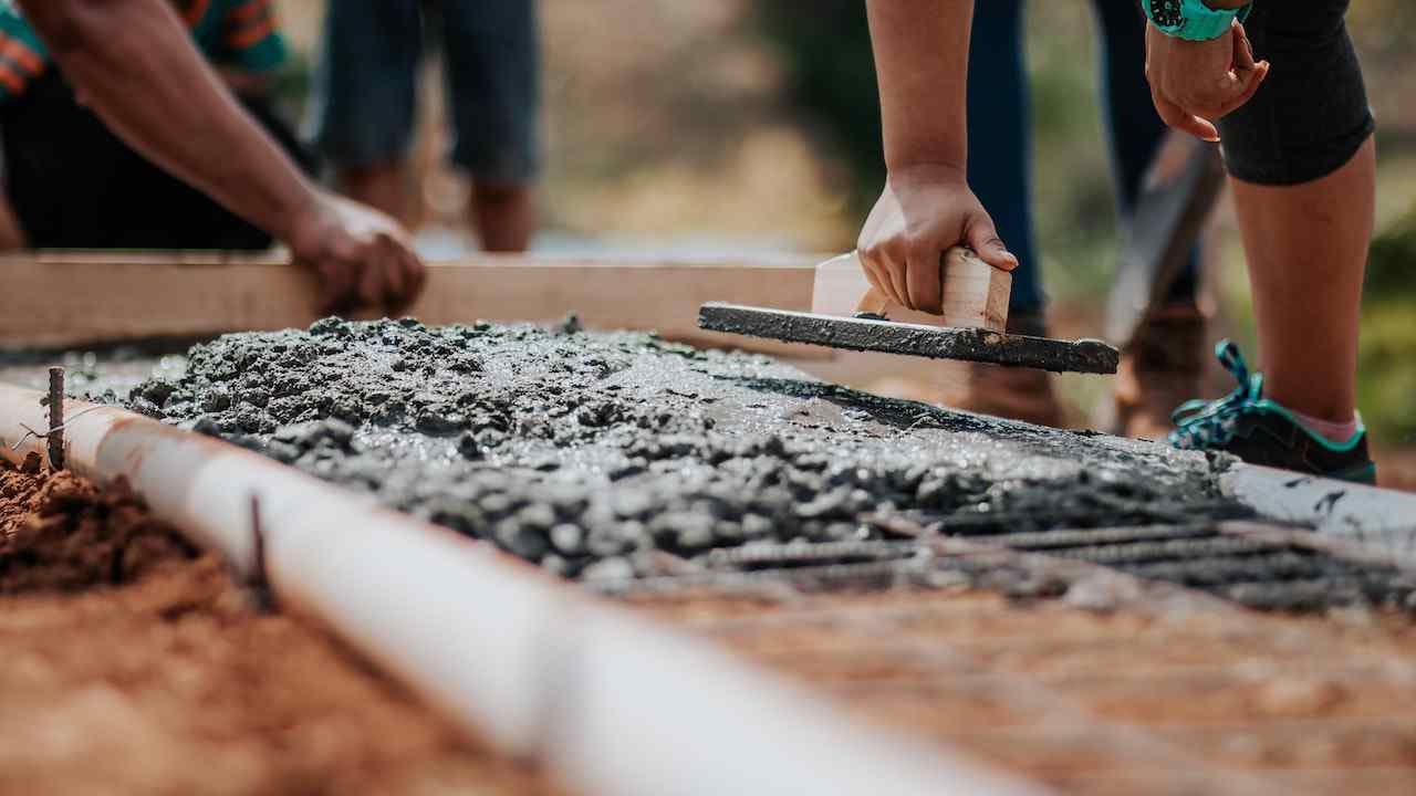 Mano di un operaio che stende la malta per costruire un muretto