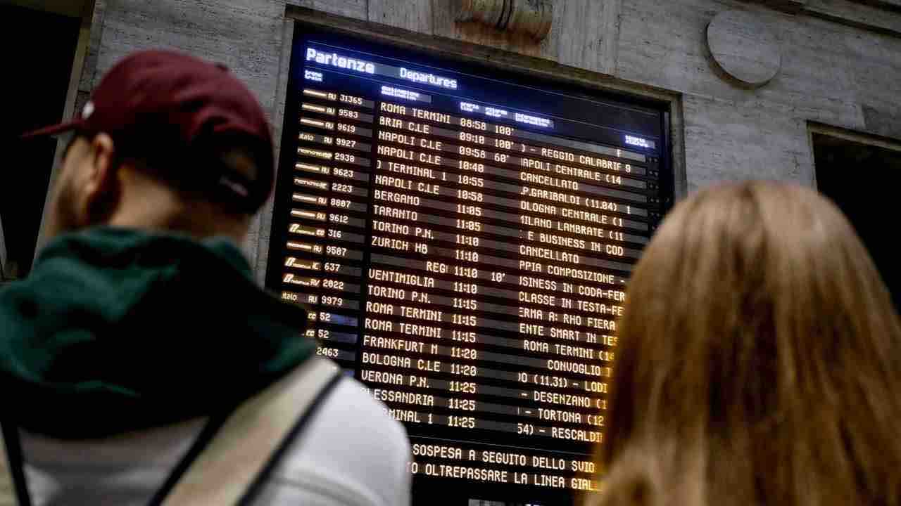 Persone che guardano il tabellone in stazione