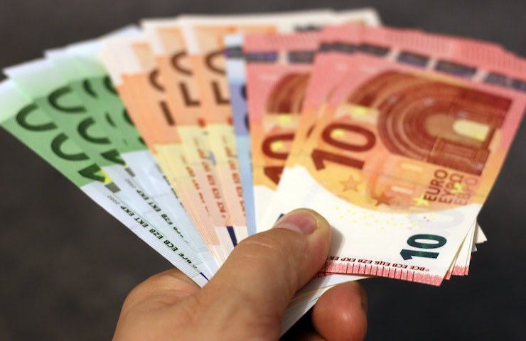 Una mano porge delle banconote di euro