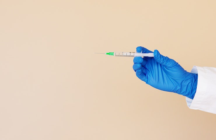 Mano mostra una siringa contenente un vaccino