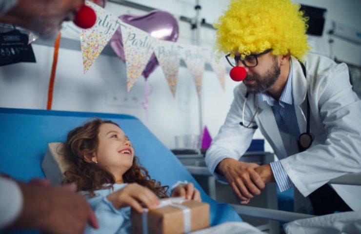 Dottore vestito da clown cerca di far stare meglio la sua giovane paziente con la clownterapia