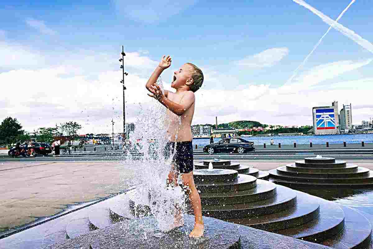 Bambino si bagna nella fontana per difendersi dal caldo torrido estivo