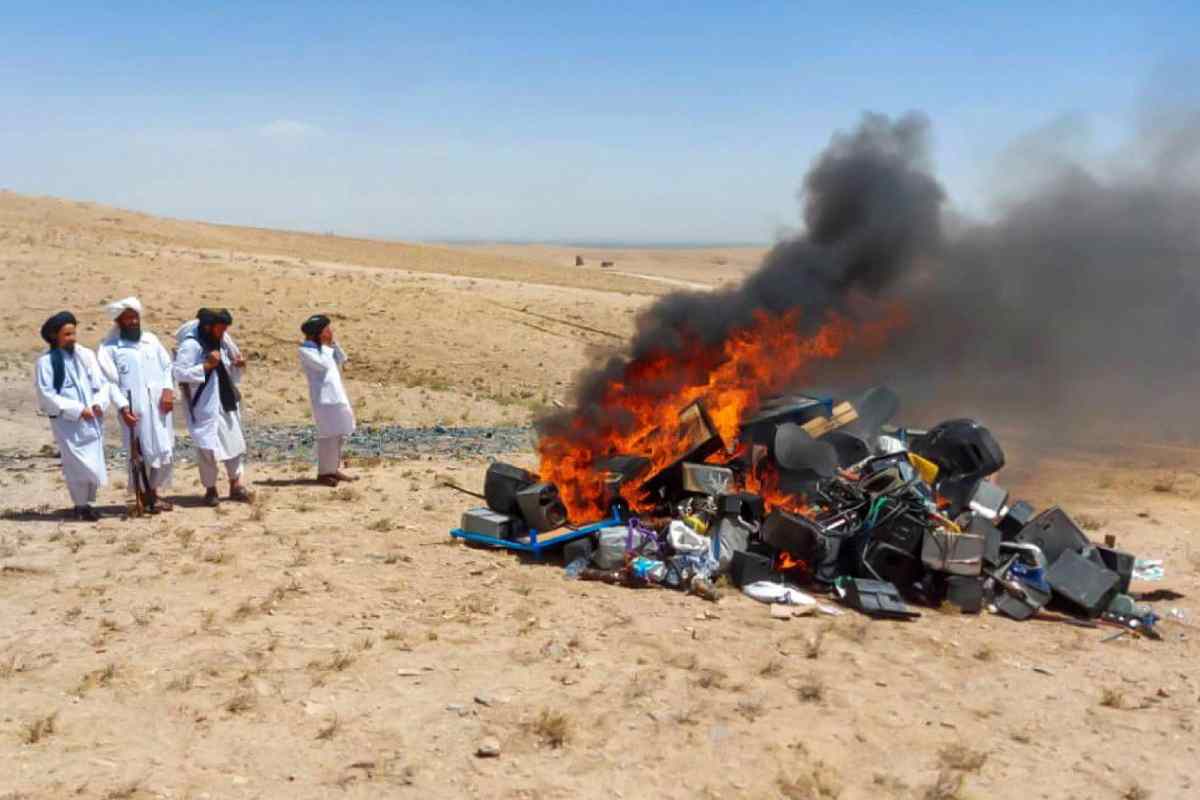 Falò di strumenti musicali in mezzo al deserto con quattro talebani nel lato sinistro