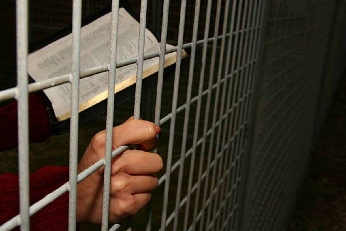 Uomo di fede cristiana legge una Bibbia in carcere