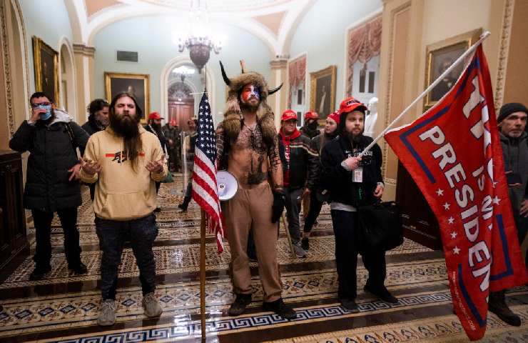 Una serie di persone travestite da sciamani con bandiere americane dentro al Congresso degli USA