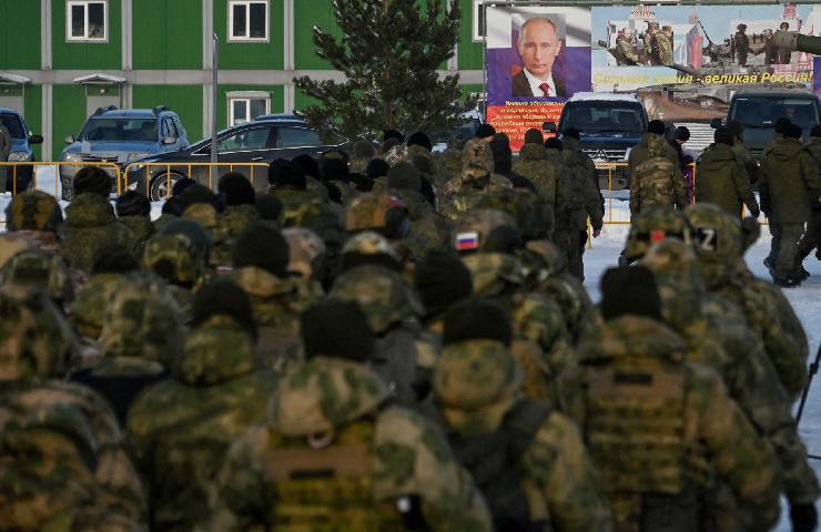Riservisti russi reclutati durante una mobilitazione parziale delle truppe camminano verso uno striscione del Presidente russo Vladimir Putin durante una cerimonia prima della loro partenza a Omsk, Russia, 6 gennaio 2023.