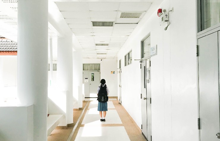 Ragazzina a scuola in un deserto corridoio