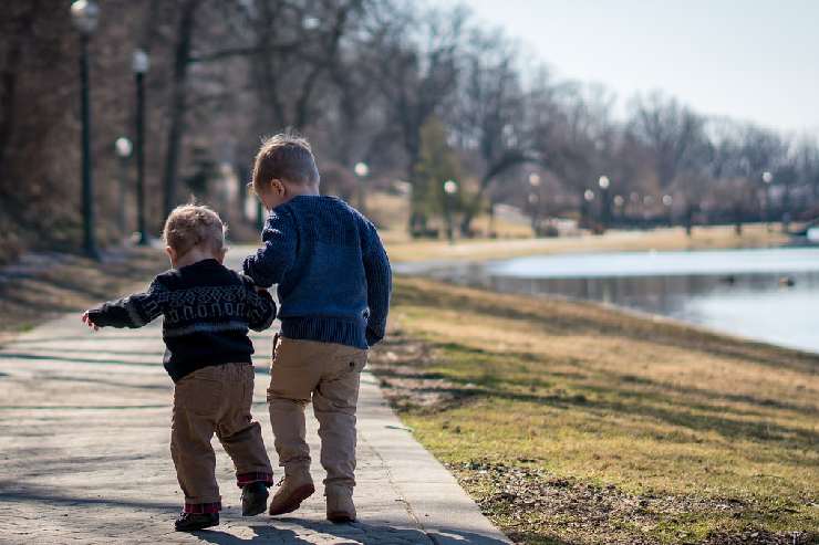 Due bambini di spalle lungo le rive di un lago