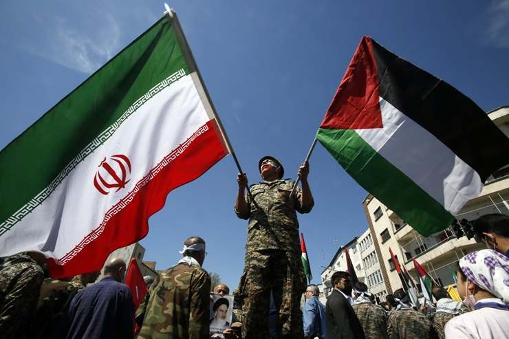 Un uomo sventola le bandiere di Iran e Palestina