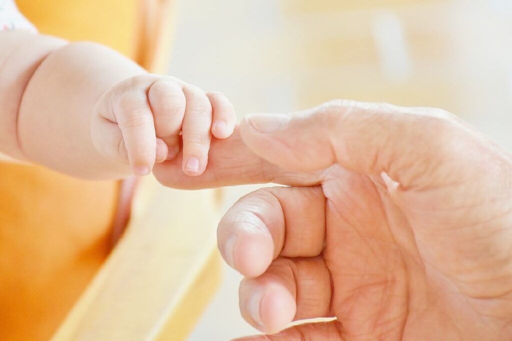 Un neonato stringe il dito di un adulto